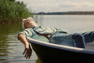 Senior man relaxing in rowing boat on a lake