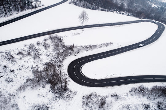 Austria, Wienerwald, cars driving on mountain road in snow-covered landscape, aerial view