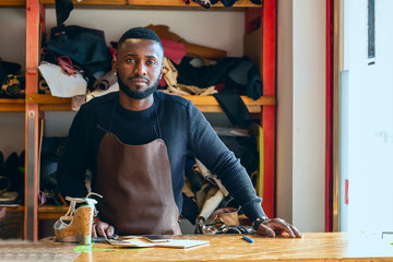 Young cheerful shoemaker in workshop.