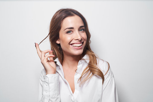 Portrait of laughing young woman twirling strand of hair