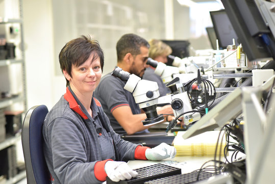 Portrait of smiling woman working on quality control in the manufacturing of circuit boards for the electronics industry