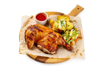 Roasted chicken legs served with potato and tomato sauce on paper at wooden tray isolated at white background.