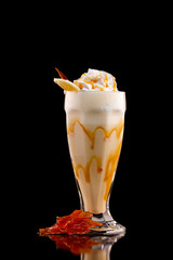 Closeup glass of caramel milk shake isolated at black background.