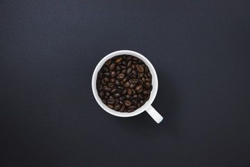 Coffee beans in a white coffee mug placed on a black background
