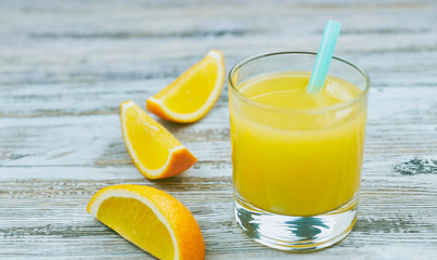 a glass of fresh orange juice with fresh citrus fruits on a light wooden table. horizontal view. citrus juice