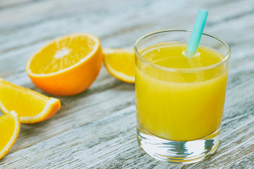 Naklejka na ściany i meble a glass of fresh orange juice with fresh citrus fruits on a light wooden table. horizontal view. citrus juice