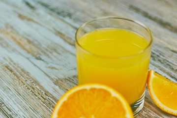 a glass of fresh orange juice with fresh citrus fruits on a light wooden table. horizontal view. citrus juice