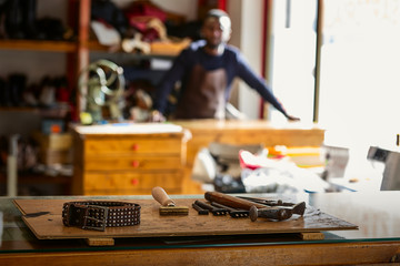 Young cheerful shoemaker in workshop.