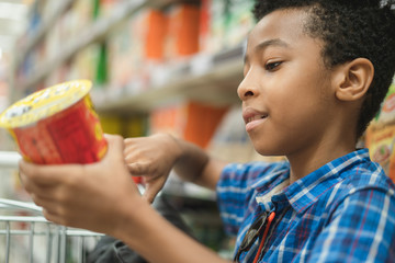 Young afro American kid reading chips label on a supermarket mall