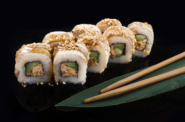 sushi roll with sesame and eel on black background