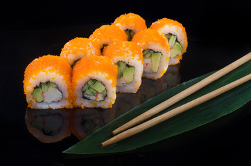sushi roll with flying fish roe on black background