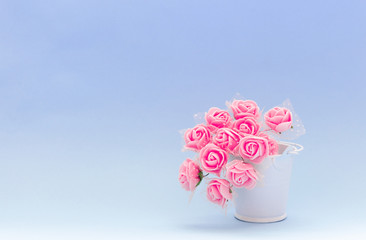 Red flowers in a white toy bucket on a blue or purple background, flowers for the holiday of March 8 or February 14, women's day