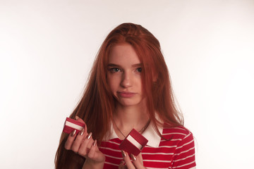 The portrait of an young redhead lady with a gift box in her hands isolated over white background...