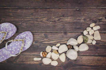 Obraz na płótnie Canvas Rocks seashells and purple slippers on wooden deck.