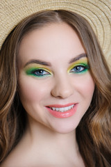 Obraz premium The girl with bright makeup posing in a straw hat