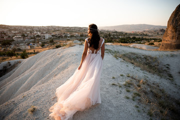 Fototapeta na wymiar Bride in a flowing dress in a stunning landscape of mountains