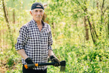 Senior man with axe chopping wood. Elderly arborist man working in garden. Active retirement lifestyle concept.