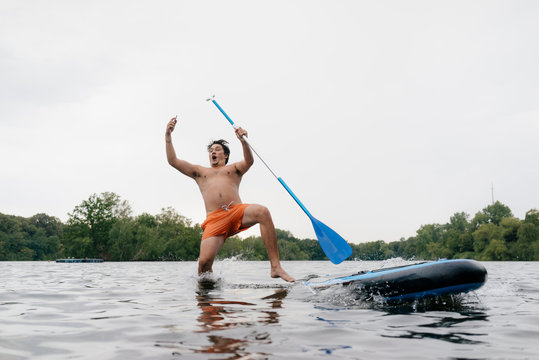 Man falling from SUP board while taking a selfie