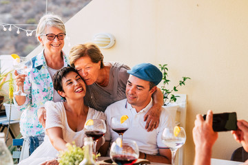 Family portrait with young couple and mothers in the background - people smile and enjoy the cocktail celenbration together at home or restaurant - kiss and parentship
