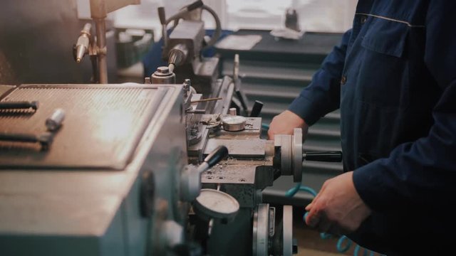 Workman in uniform working on lathe machine, close up. Concept of industry