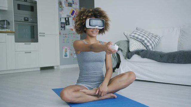 Cheerful sportswoman in VR glasses at home