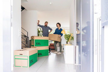 Portrait of couple in new home with cardboard boxes