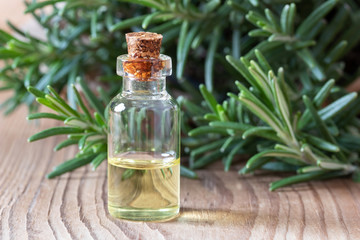 A bottle of rosemary essential oil with fresh rosemary