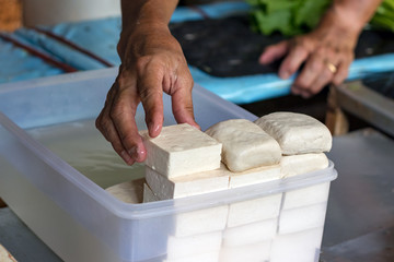 Male hand stacking tofu cheese.