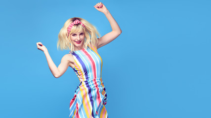 Obraz na płótnie Canvas Fashionable shapely Young woman smiling on blue background. Excited blonde Girl Having Fun dance in Trendy summer dress, Stylish fashion sneakers, makeup. Happiness funny concept