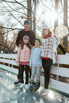 Family leaning on railing at the ice rink