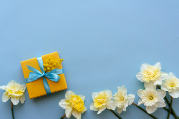 Gift box and white narcissus flowers. Beautiful gift box and fresh flowers on blue background
