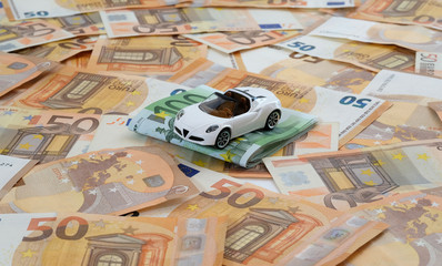 Ein Modellauto auf flächendeckend ausgelegten 50-Euro-Banknoten mit 100-Euro-Banknoten zum Thema...