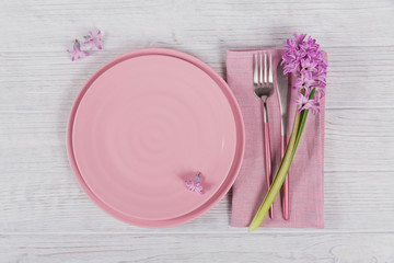 Pink rustic place setting with purple hyacinth flower and linen napkin on white wooden background