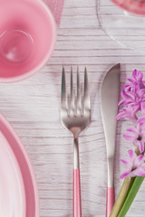 Pink rustic table setting with purple hyacinth flowers, linen napkin and glass of rose wine on white wooden table