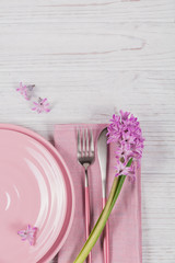 Pink rustic place setting with purple hyacinth flower and linen napkin on white wooden background