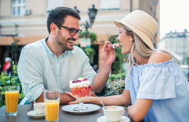 Dating in the cafe. Loving couple drinking coffee and eating fruit desserts. Dating, love, relationships