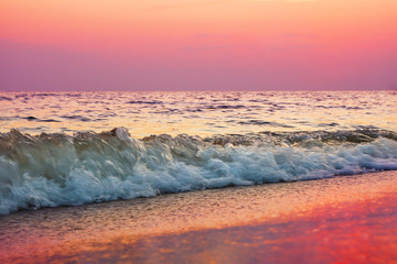 Red violet pink ocean beach evening sunset. Colorful close up waves. Sun reflection