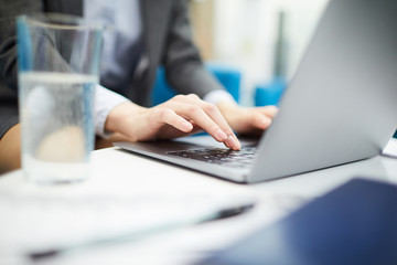 Fototapeta premium Closeup of unrecognizable businesswoman typing on keyboard while using laptop in office, copy space