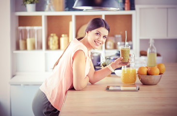 Beautiful young woman using a digital tablet in the kitchen.