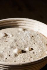 Sourdough bread proofing in a basket with visible gas bubbles. Homemade baking.