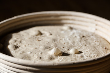 Sourdough bread proofing in a basket with visible gas bubbles. Homemade baking.