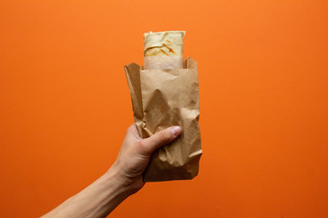 Shawarma sandwich with ingredients in the hand. Sandwich in pita bread. Burrito - obrazy, fototapety, plakaty