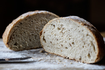 Fresh homemade bread made of sourdough resting on wooden cuttnig board. Artisan bread with golden crispy crust.