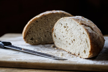 Fresh homemade bread made of sourdough resting on wooden cuttnig board. Artisan bread with golden crispy crust.
