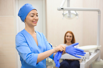 Obraz premium A young female doctor preparing herself for working, putting on protective gloves.