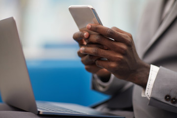 Close up of unrecognizable African businessman using smartphone while working in office, copy space
