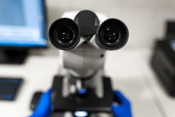 Closeup point of view of laboratory assistant looking through microscope lens