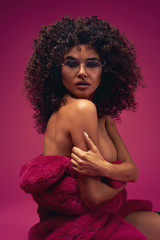 portrait of a half naked model in a fur coat on a bright background