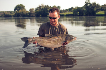 Happy angler with carp fishing trophy.Amur (grass carp).Fish trophy