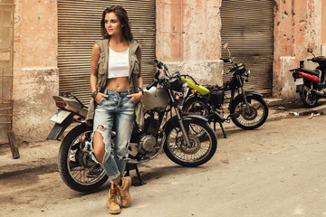 Woman is posing beside old motorcycles - Powered by Adobe